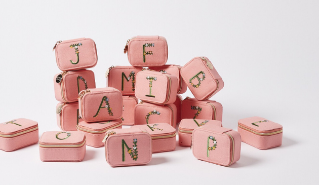 a pile of pink jewellery cases with green letters on