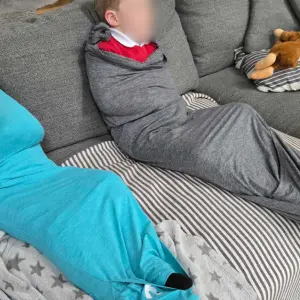 Two children wear the Nesti Compression Pod while sat on their sofa at home during testing