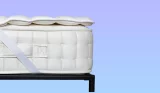A mattress with a cooling mattress topper against a blue background