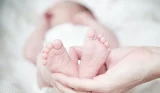 parent holding newborn baby's feet