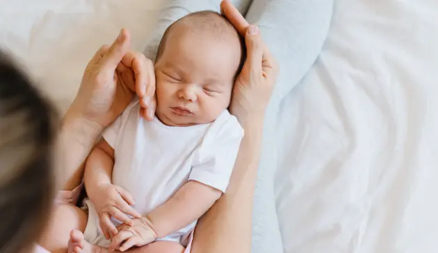 Sleeping newborn being held and cuddled by mother