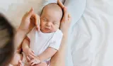 Sleeping newborn being held and cuddled by mother