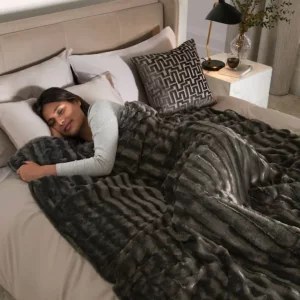 A woman lies underneath the Next Grey Faux Fur Weighted Blanket