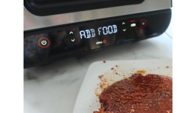 A piece of steak, seasoned, ready to go in the Ninja Foodi Max AG551UK Health Grill & Air Fryer