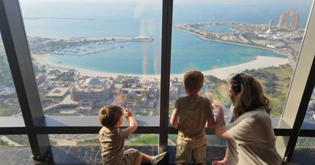 Rebecca Roberts and her children looking out the window at Observation Deck at 300 in Abu Dhabi
