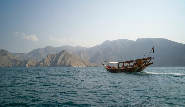 A boat ontop of the water with rugged mountains in the background