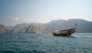 A boat ontop of the water with rugged mountains in the background