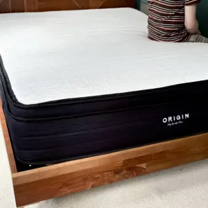 Someone sitting on the Origin Hybrid Pro Mattress