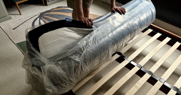 A man opens the Origin Hybrid Pro Mattress  from its packaging