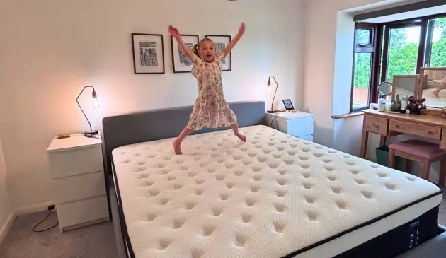 A young girl jumps on top of an Origin LumbarCloud mattress