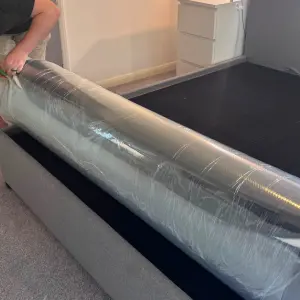 A man cuts the plastic packaging of the Origin LumbarCloud mattress
