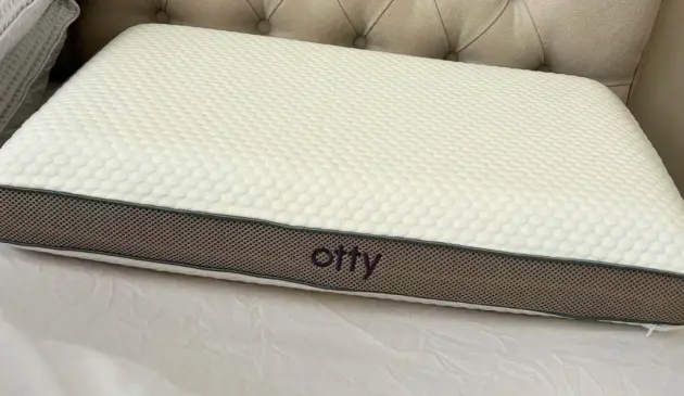 A close up of the Otty Deluxe Pure Pillow on a tester's mattress