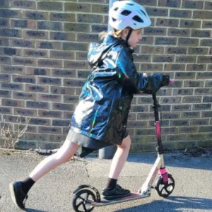 A primary school aged girl in a white helmet riding a pink and black scooter