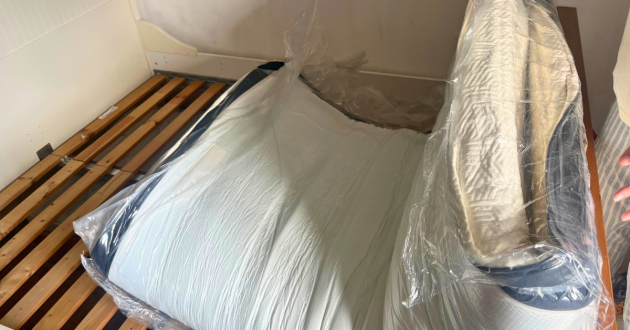 Rolled Panda Hybrid Bamboo Mattress Pro unfolding on a wooden slatted bed while still inside its plastic wrapping