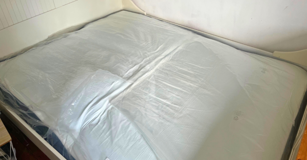 Panda Hybrid Bamboo Mattress Pro lying flat on a bed frame, still covered by its inner plastic wrapping