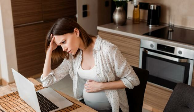Woman on laptop holding baby bump
