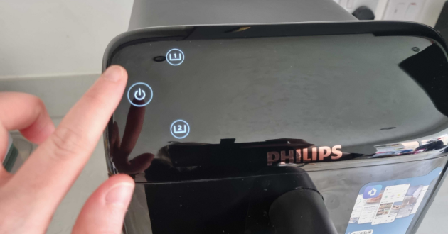 A finger turns on and off the Philips 4000 Series NA462/79 Stacked Dual Basket Air Fryer