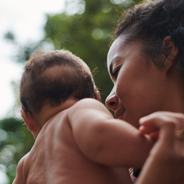 A woman looks lovingly at her baby's face who is turned away from the camera