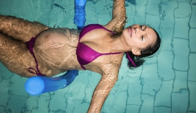 pregnant woman lying on back in swimming pool