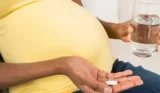 pregnant woman with glass of water and medication