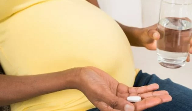 pregnant woman with glass of water and medication