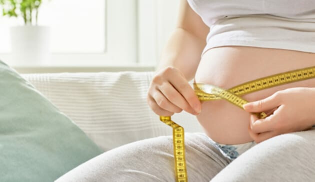 Pregnant woman measuring bump