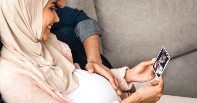 Pregnant woman and partner looking at scan photo