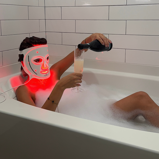 Woman using Project E Beauty LED face mask in bath