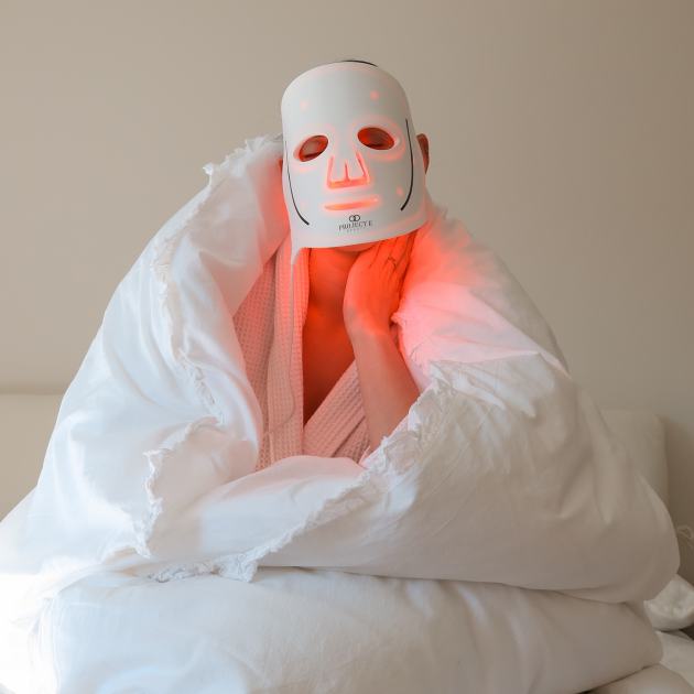 Woman using Project E Beauty LED face mask in bed