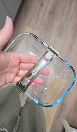 A hand holds the Pyrex Airfryer Dish with Removable Handle