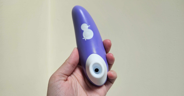 A hand holding the Lovehoney x ROMP Switch clit sucker against a wall