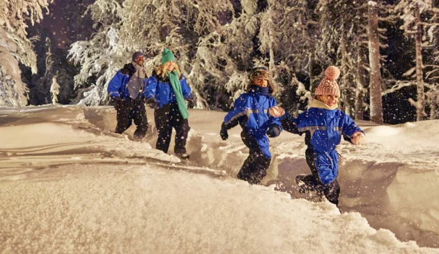 A family walks through a snowy forest in Finnish Lapland