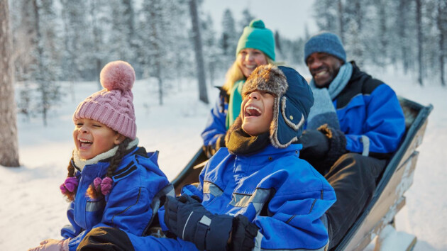 A family riding on a husky sleigh in Finnish Lapland on a Santa's Lapland holiday