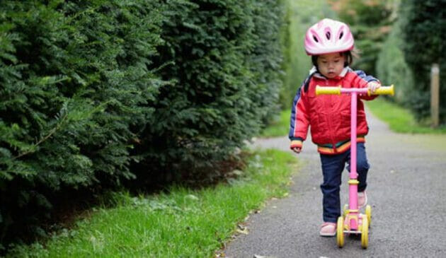 child in helmet with scooter
