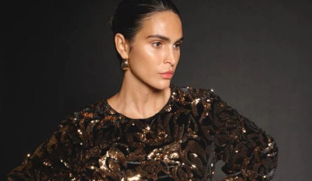 A model wears a sparkly dress against a black background for Monsoon
