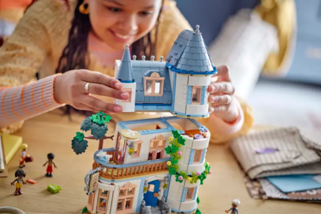 A young girl plays with a Friends LEGO house