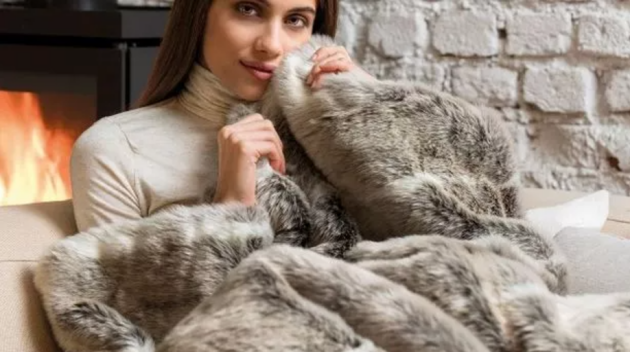 A woman holding the Dreamland Intelliheat Faux Fur Warming Throw