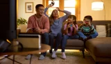 A picture of a family playing the Nintendo Switch together on their sofa