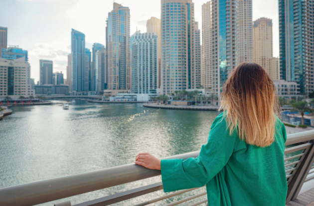 A blonde, expatriate woman looking over Dubai Marina from a bridge
