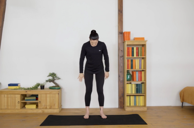 A woman performs Grounding breath on her yoga mat in her living room