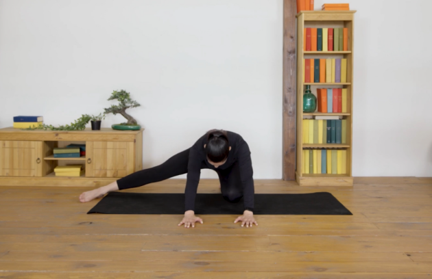 A woman performs Side stretches on a yoga mat in her living room
