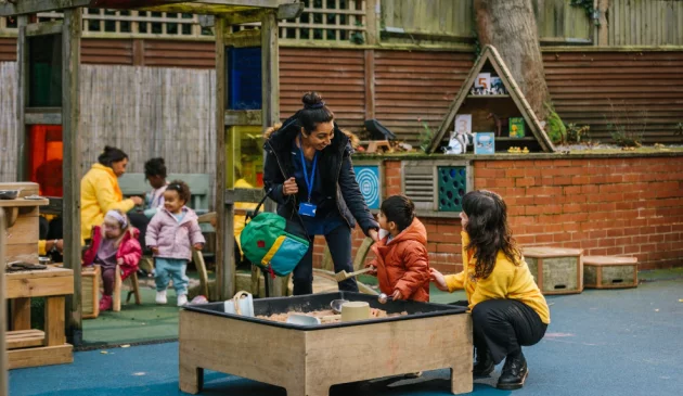 A mum greets her child in the playground at nursery