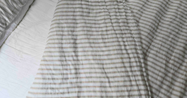 The Secret Linen Store French Ticking Stripe Natural bedding set folded back atop Rebecca's bed
