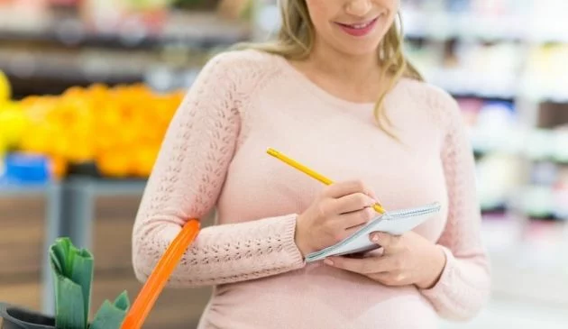 woman writing shopping list at supermarket