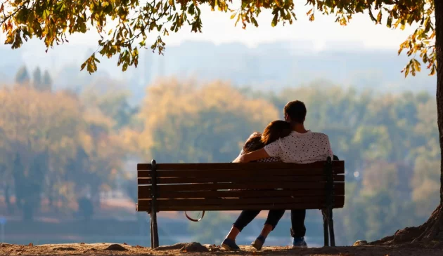 A couple sit on a bench looking into the distance