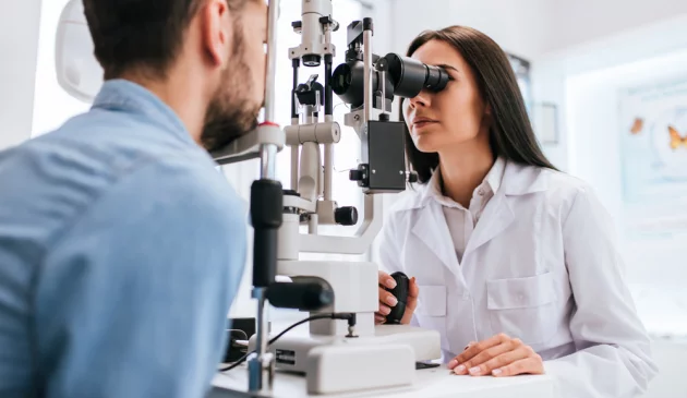 A female optometrist examining a man's eyes using a scanner