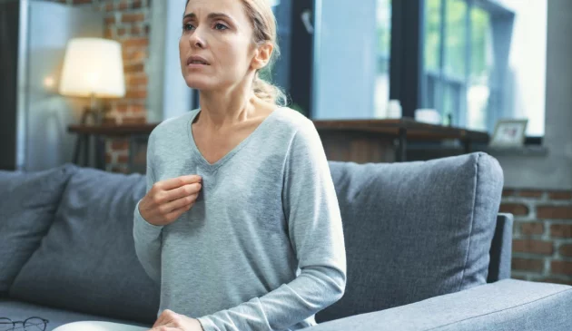 A woman is tired sat on her sofa