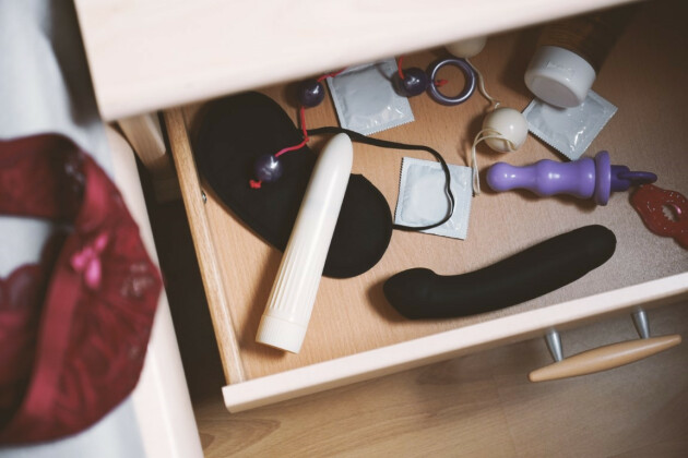A birds eye view of a bedside drawer with sex toys and accessories inside