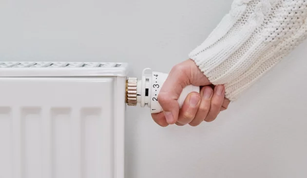 A woman's hand turning the dial on a radiator