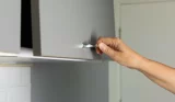 A woman's hand opens a cupboard
